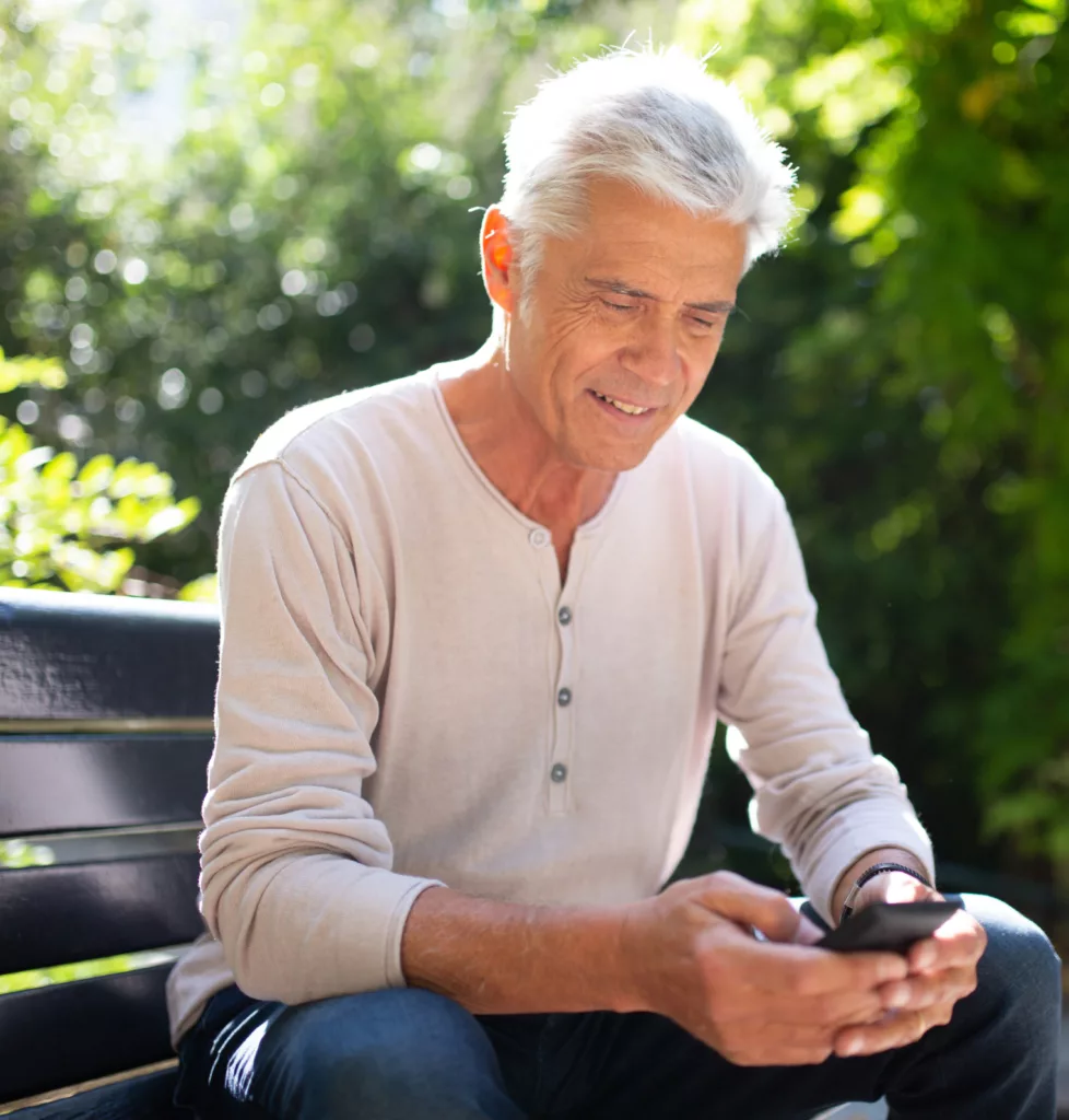 Man sitting on park bench interacting with phone